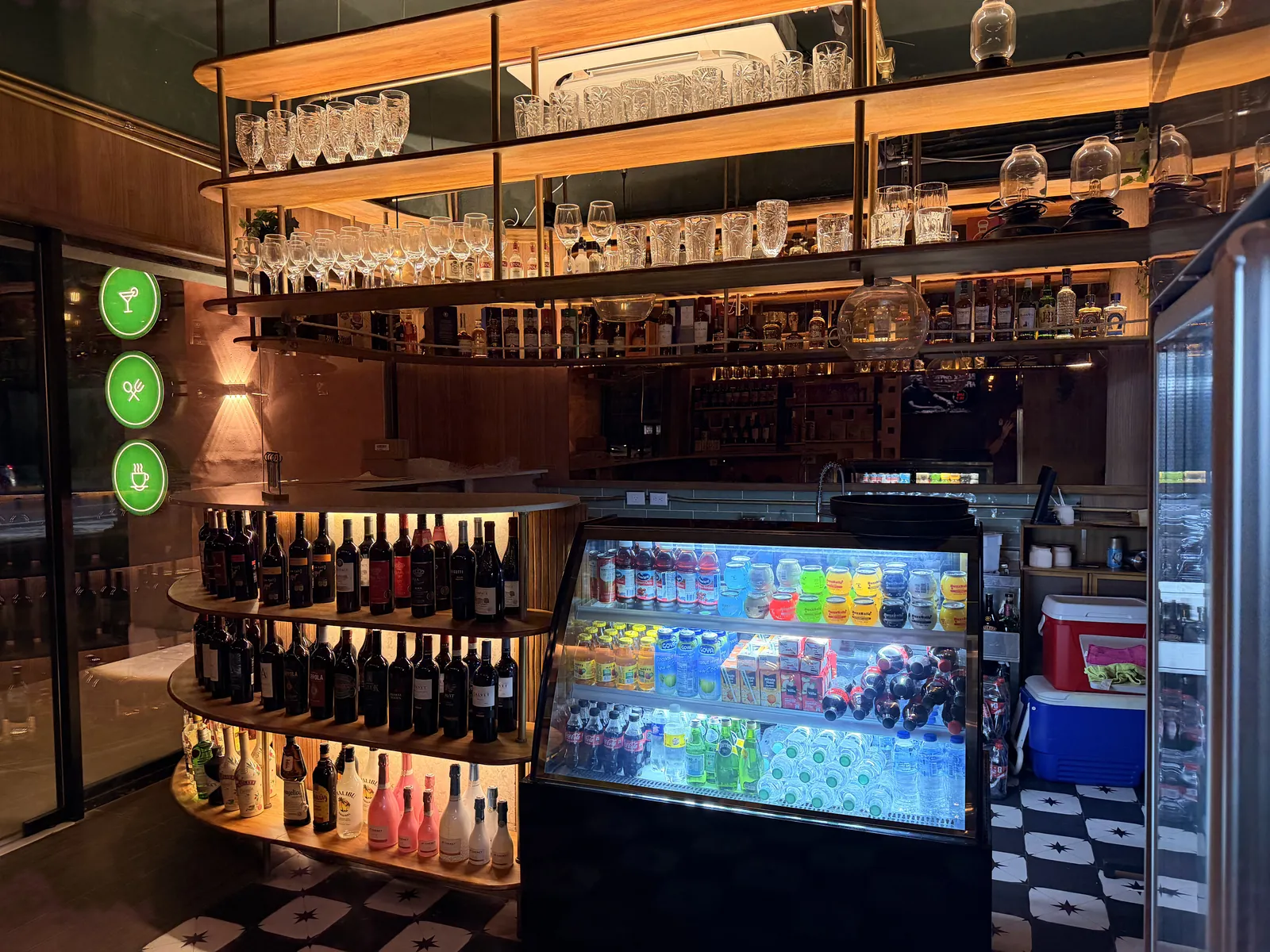Inside the lounge: lit shelves of wine and spirits, glassware above and a drinks cooler